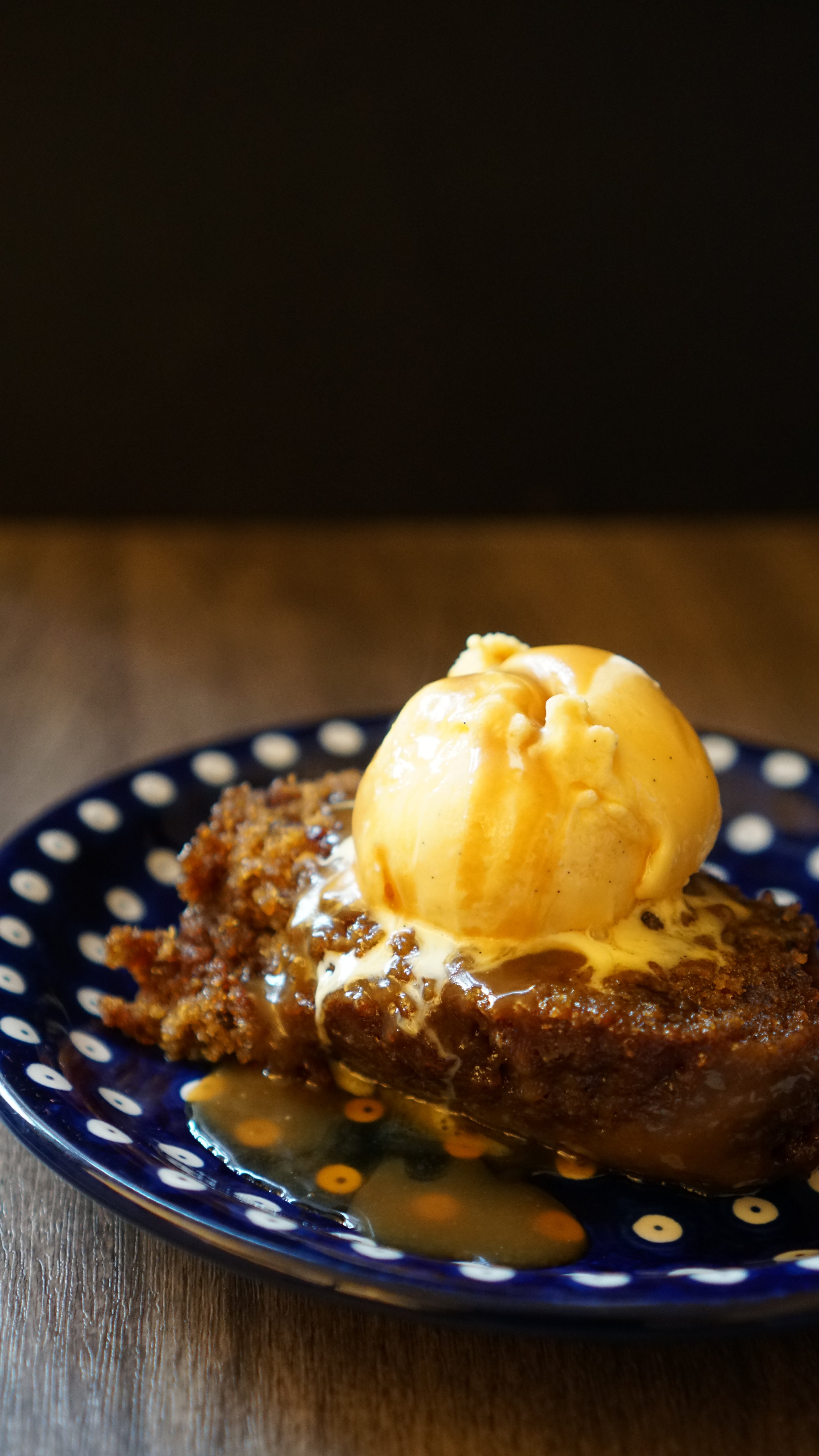Sticky Toffee Pudding with a scoop of vanilla ice cream, drizzled with homemade toffee sauce